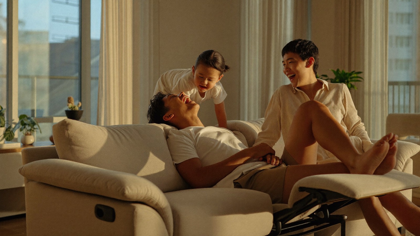 A family relaxing together on a recliner sofa in warm afternoon light