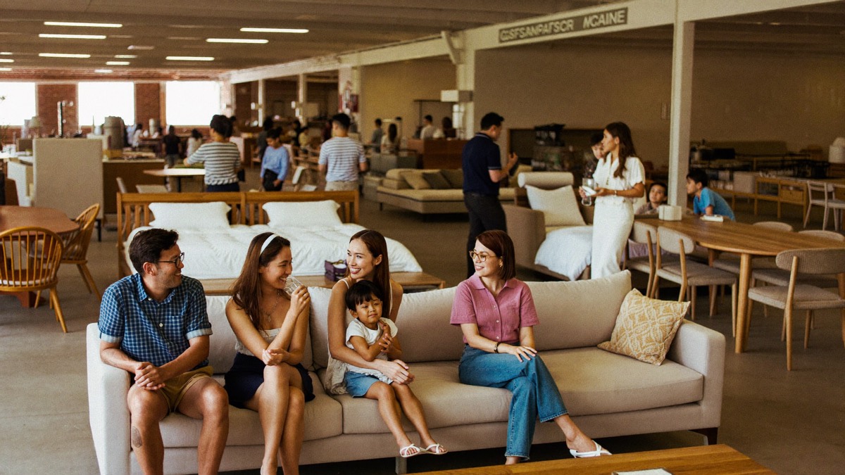 Visitors browsing sofas and beds at a furniture showroom event